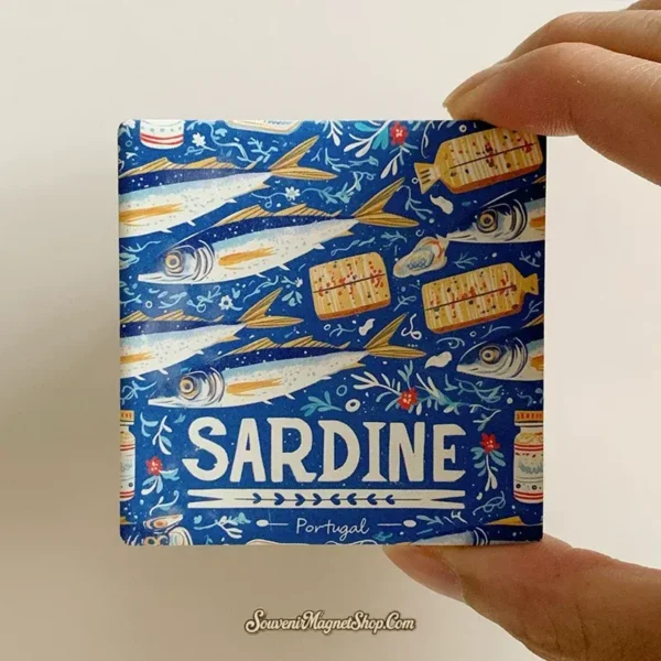 Hand holding Portugal sardine ceramic souvenir magnet showing blue tile design and compact size