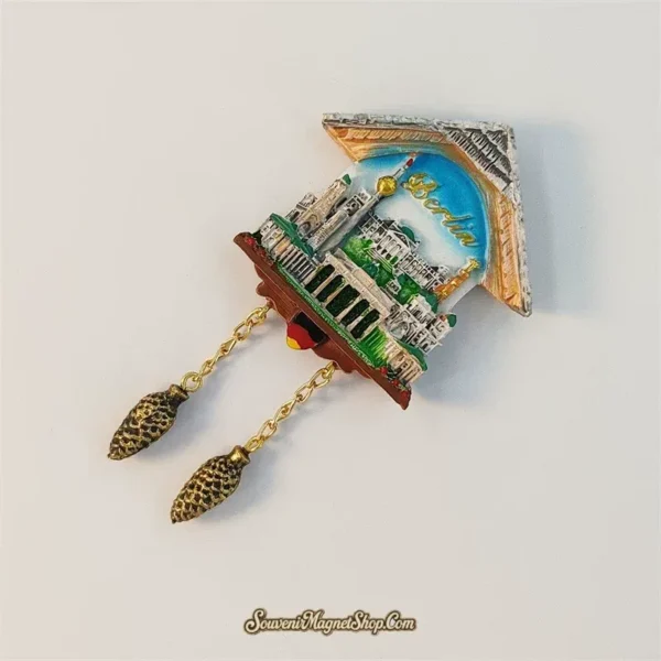 Angled view of Berlin cuckoo clock magnet showing chalet roof and dangling pine-cone weights