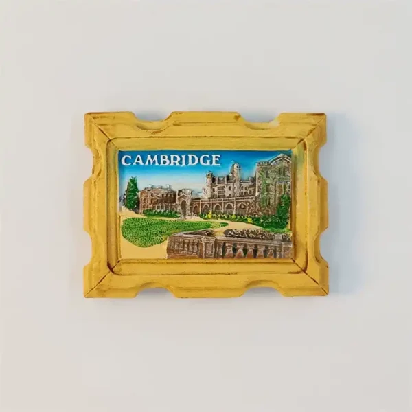 Front view of a Cambridge University fridge magnet with a carved gold frame and hand-painted college buildings under a blue sky