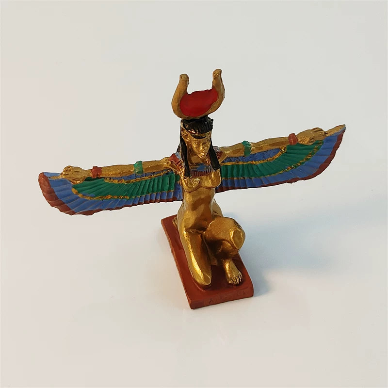 Gilded winged Isis souvenir figurine at an angle, green and blue painted feathers on red hieroglyph base