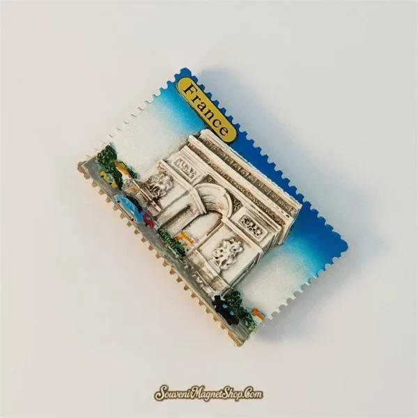 Angled view of the Paris Arc de Triomphe souvenir magnet showing the raised carved facade and blue stamp border