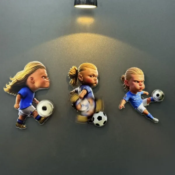 Three big-headed Haaland caricature fridge magnets in blue kits, each kicking a spinning ball under a spotlight