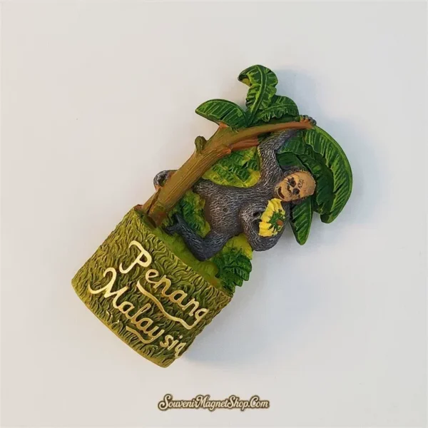 Angled view of Penang monkey souvenir magnet showing 3D resin banana tree detail