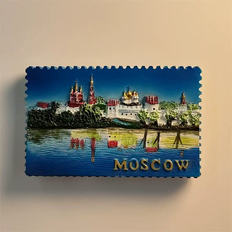 russia-moscow-novodevichy-convent-fridge-magnet-front Front view of a stamp-shaped Moscow fridge magnet showing Novodevichy Convent reflected in water with gold MOSCOW lettering