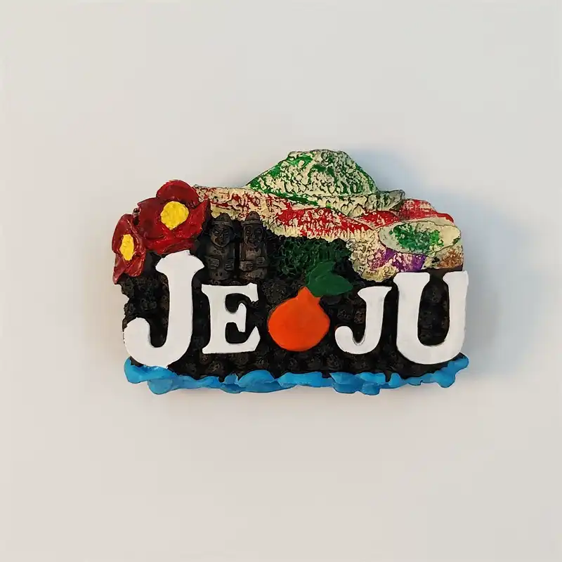 Front view of the 3D Jeju Island fridge magnet spelling JEJU with a tangerine, red camellias and dol hareubang statues