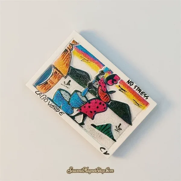 Angled view of Cape Verde souvenir magnet showing folk art village scene and CABO VERDE lettering