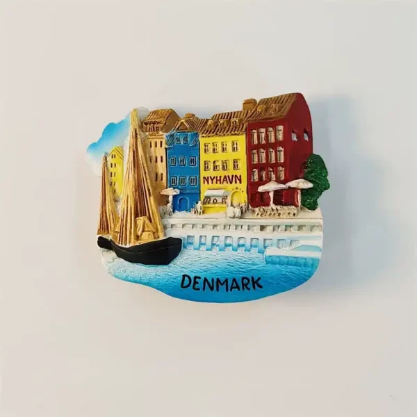 Front view of a hand-painted Nyhavn fridge magnet showing Copenhagen's colorful canal houses, an old wooden sailboat and DENMARK lettering in 3D relief.