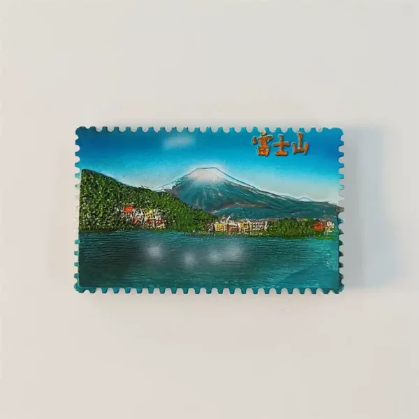 Japan Mount Fuji stamp-shaped fridge magnet showing the mountain above a lake and lakeside town, front view