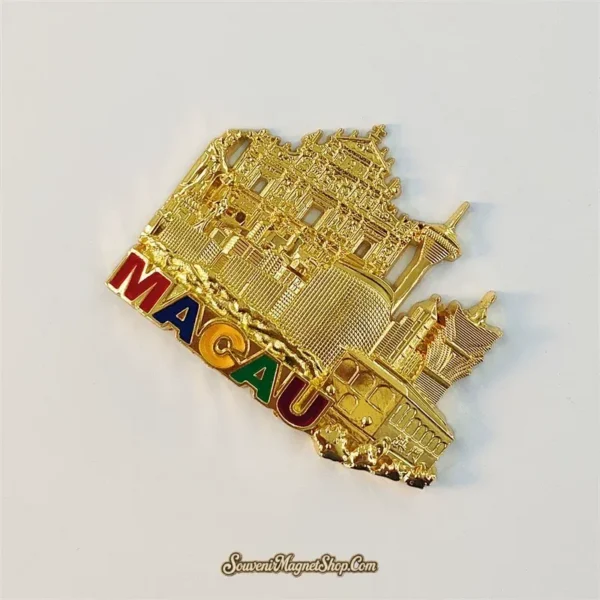 Left-angled view of the gold Macau souvenir magnet showing raised landmark details and colorful MACAU letters