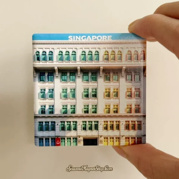 Hand holding the flat square ceramic Singapore rainbow building magnet showing its glossy printed tile