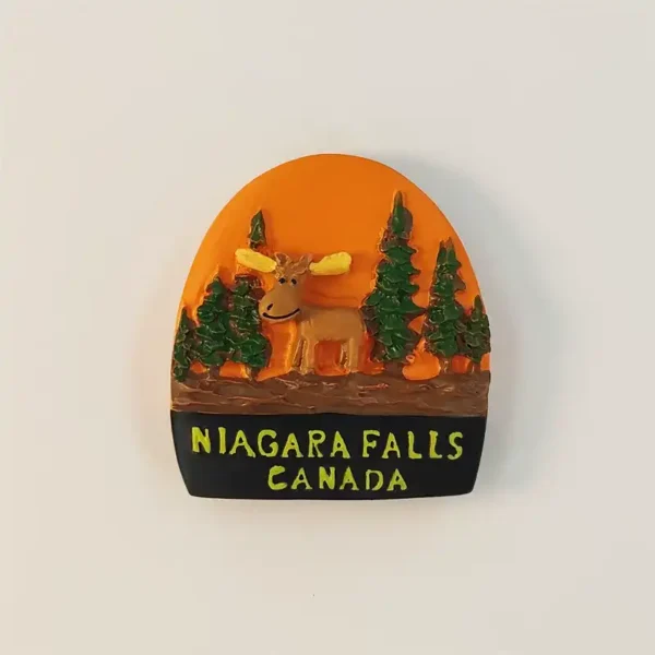 Canada Niagara Falls fridge magnet with a smiling moose, yellow antlers, evergreen trees, orange background, and black destination plaque.