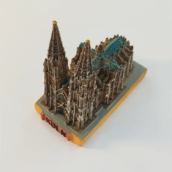 Angled view of the Cologne Cathedral landmark figurine showing twin spires, turquoise roof sections and the rectangular base.