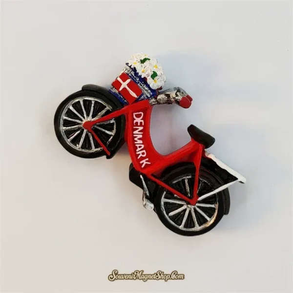 Angled view of the Denmark bicycle fridge magnet showing its raised red frame, daisy basket, flag panel, saddle, and rear rack.