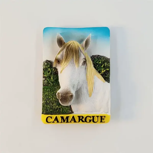 Front view of the France Camargue white horse fridge magnet showing the white horse's head with a blond mane, green marsh scrub, and a yellow CAMARGUE banner.
