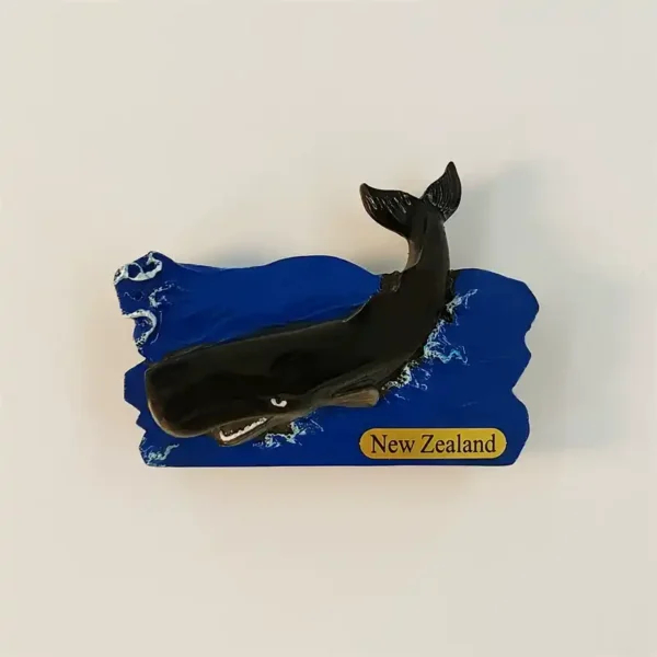 Kaikoura sperm whale fridge magnet with a dark whale, raised tail, blue waves and a yellow New Zealand nameplate.