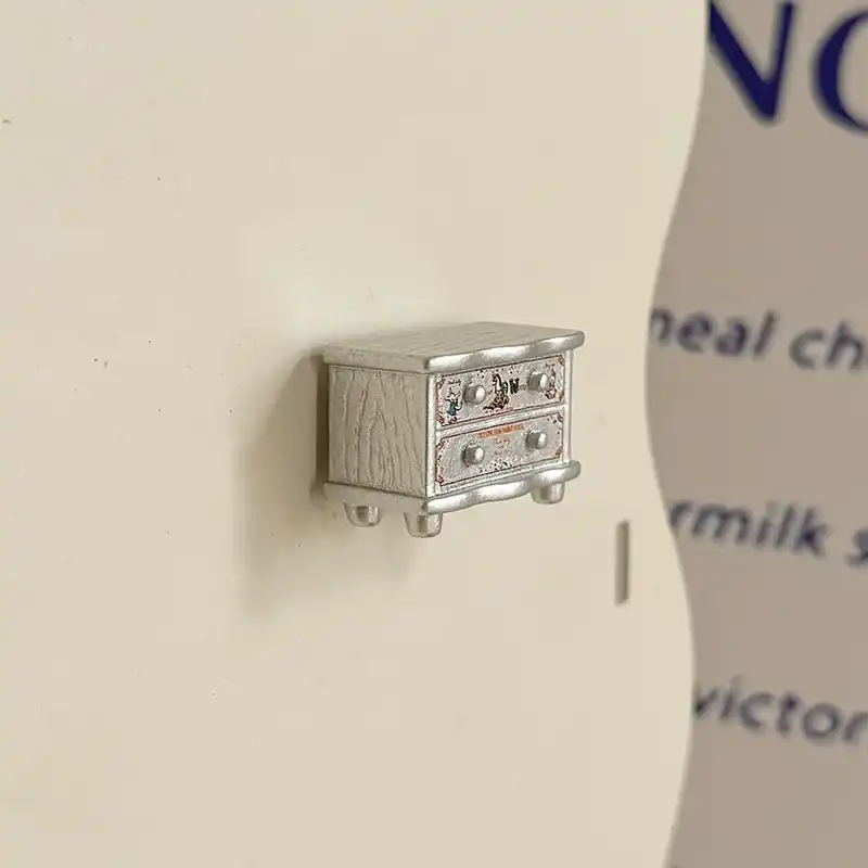 silver-bedside-cabinet-cute-fridge-magnet-front Cute silver bedside cabinet fridge magnet with two drawers, round knobs, short feet, and textured side panels.