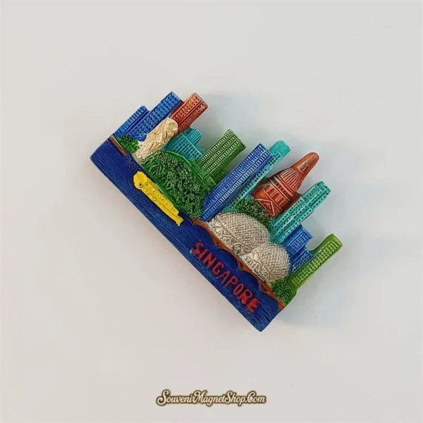 Singapore skyline magnet tilted clockwise, showing the raised Merlion, textured Esplanade domes and red SINGAPORE lettering.