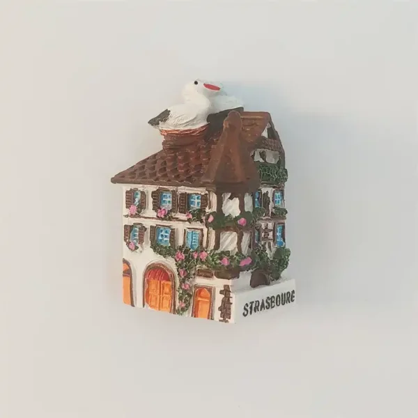 Strasbourg half-timbered house fridge magnet with blue shutters, flowers, orange doors, and a white stork on the roof.
