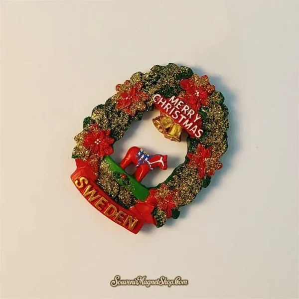 Angled view of the Sweden Dala horse wreath fridge magnet showing gold-speckled greenery, red flowers and SWEDEN ribbon.