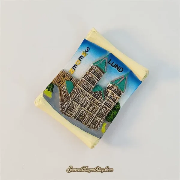 Angled left view of the Lund Cathedral fridge magnet showing the raised towers and scroll-shaped cream border in perspective.