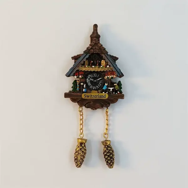Switzerland cuckoo clock fridge magnet with a steep brown roof, flower-trimmed windows, yellow nameplate and two gold-tone pinecone pendants.