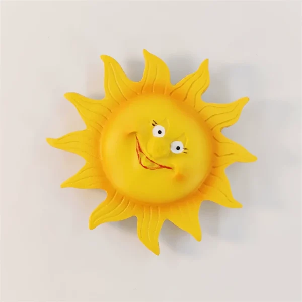 Angled view of the yellow Barcelona sun fridge magnet showing raised facial features and carved ray details.