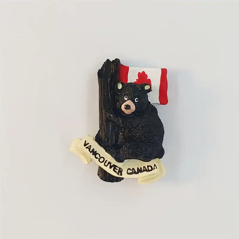 canada-vancouver-black-bear-fridge-magnet-front Front view of a Vancouver black bear fridge magnet hugging a tree, with a Canadian flag and VANCOUVER CANADA scroll.