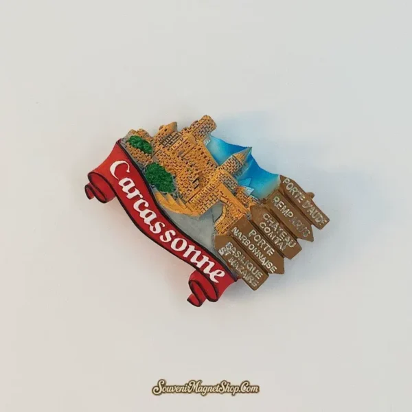 Angled Carcassonne fridge magnet showing the layered fortress, blue backdrop, red scroll, and five brown directional signs.