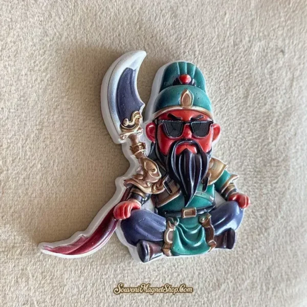Angled view of the Guan Gong fridge magnet on a textured beige background, showing the curved blade and raised beard.