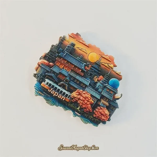 Kyoto cityscape fridge magnet tilted clockwise, showing raised rooftops, orange-pink trees and a train beneath the sunset