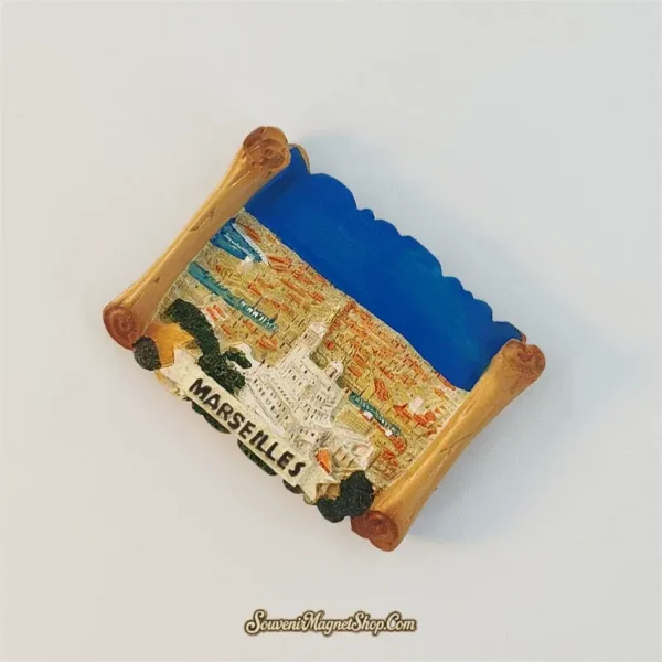 Marseille scroll-shaped fridge magnet tilted clockwise, showing the pale basilica, terracotta rooftops and curled golden edges.