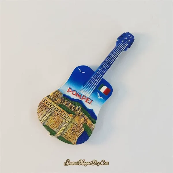 Angled Pompeii guitar fridge magnet showing the blue neck, stone-colored ruins, mountain silhouette, and Italian flag.