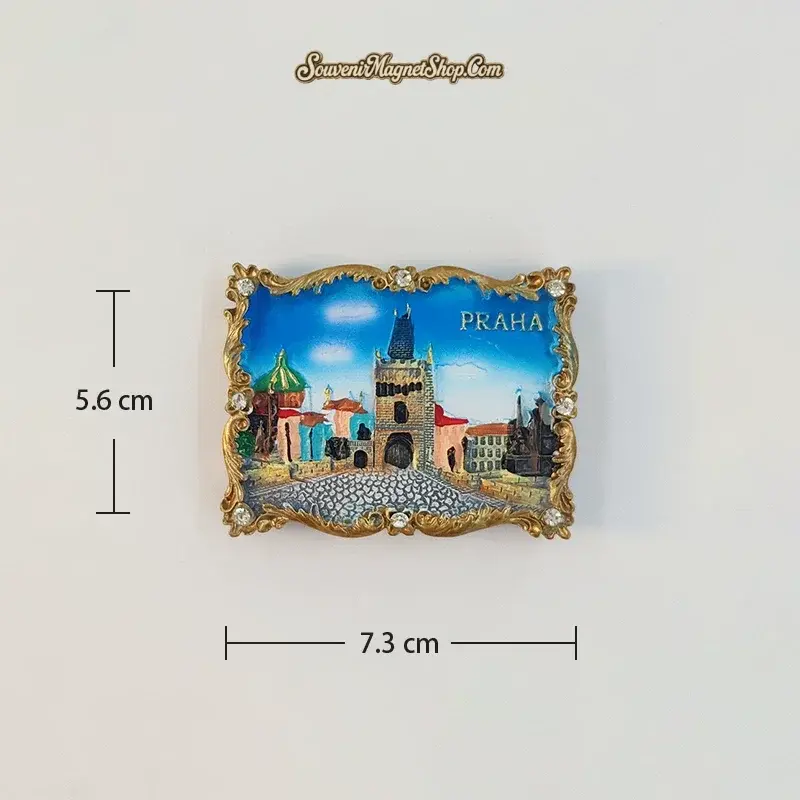 Astronomical Clock Square variant fridge magnet with a central gateway tower, cobbled foreground and PRAHA lettering inside a gold-tone border.