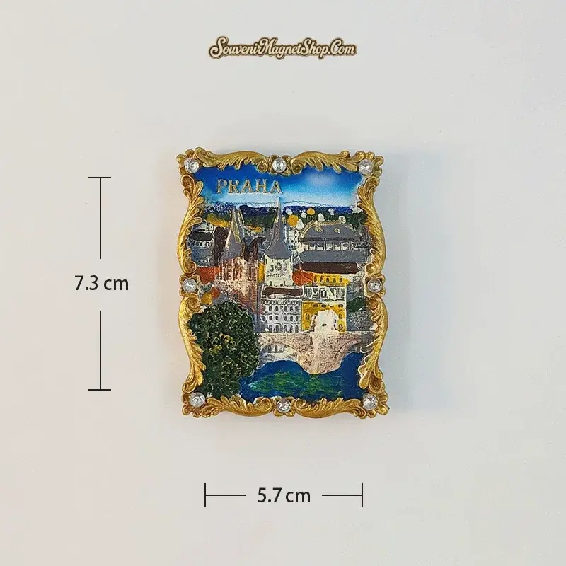 Portrait Charles Bridge A variant fridge magnet with blue water, stone bridge arches, clustered buildings and green trees in a gold-tone border.
