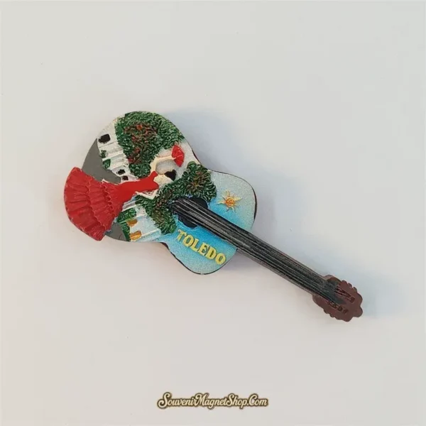 Toledo guitar fridge magnet angled with its neck pointing down to the right, showing the dancer's tiered red skirt and raised fan.