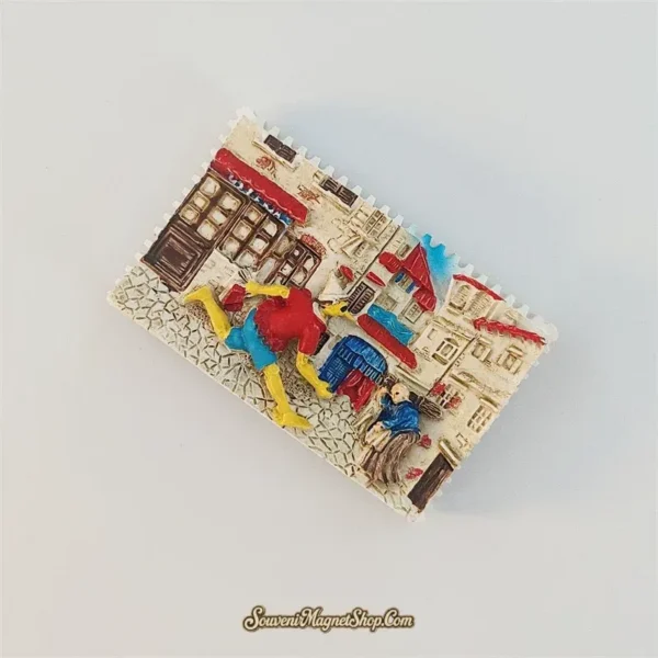 Pinocchio village street fridge magnet tilted clockwise, showing raised cobblestones, shop doors and a second figure on the right